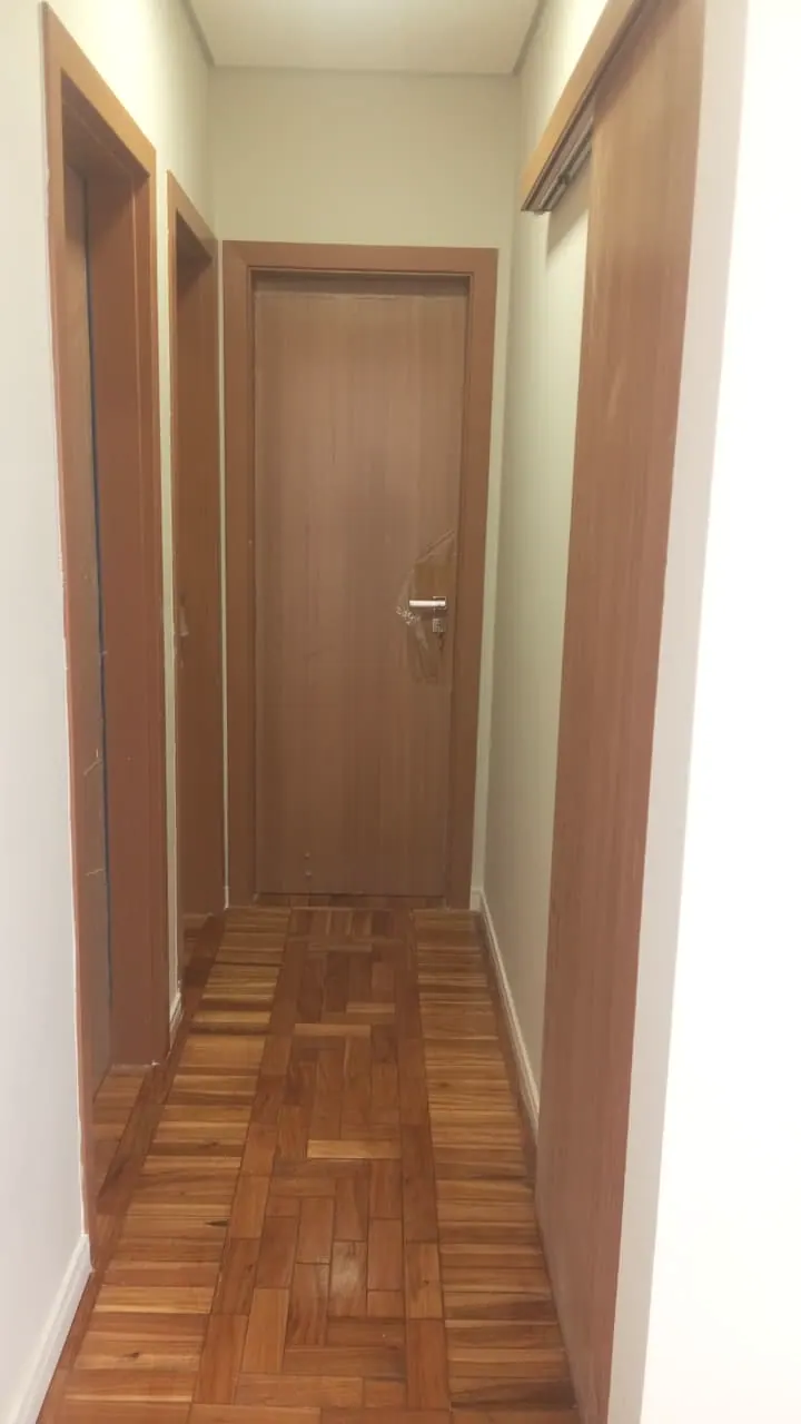 Corredor com piso de madeira e portas após a reforma